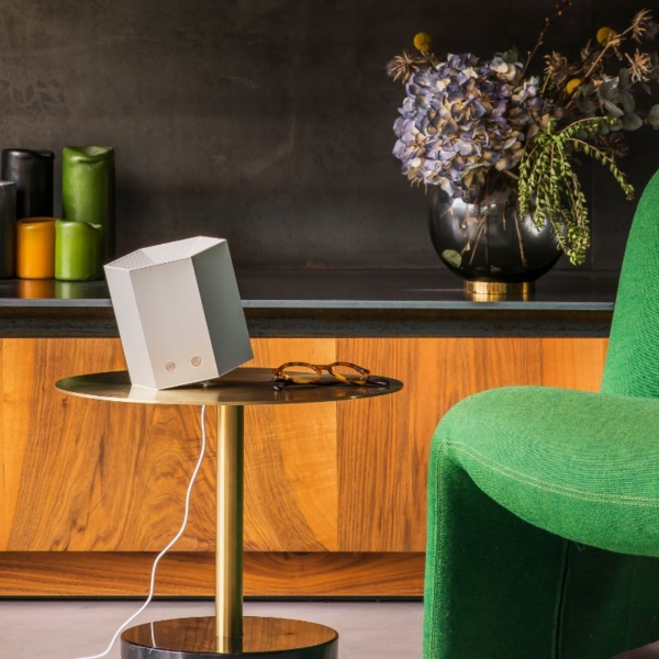 Purificateur d'air compact de Shield by JVD posé sur une table à côté d'un fauteuil vert