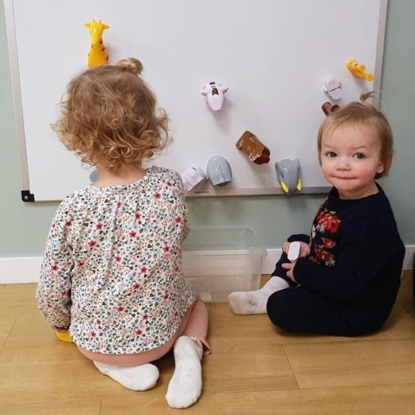 deux enfants en train de jouer sur un tableau blanc dans une crèche