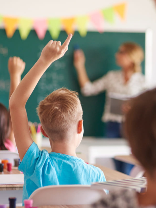 des élèves de primaires qui lèvent la main dans une salle de classe